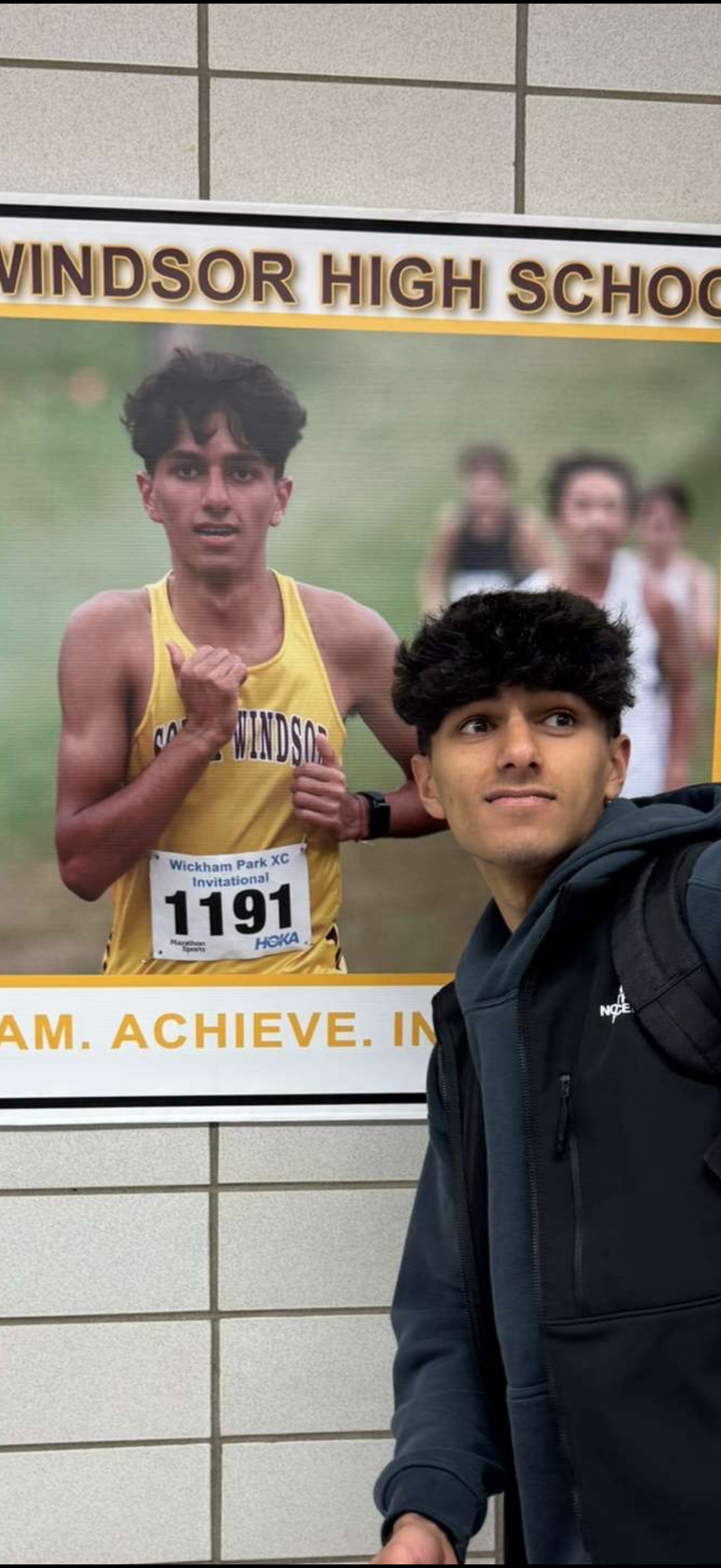 Image
          of Aarish Kodnaney in front of a picture of Aarish Kodnaney. This
          picture of Aarish Kodnaney is on the wall of his high school - South
          Windsor High School.